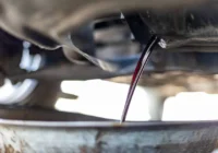 Samochód na podnośniku warsztatowym z widoczną skrzynią automatyczną i mechanikiem